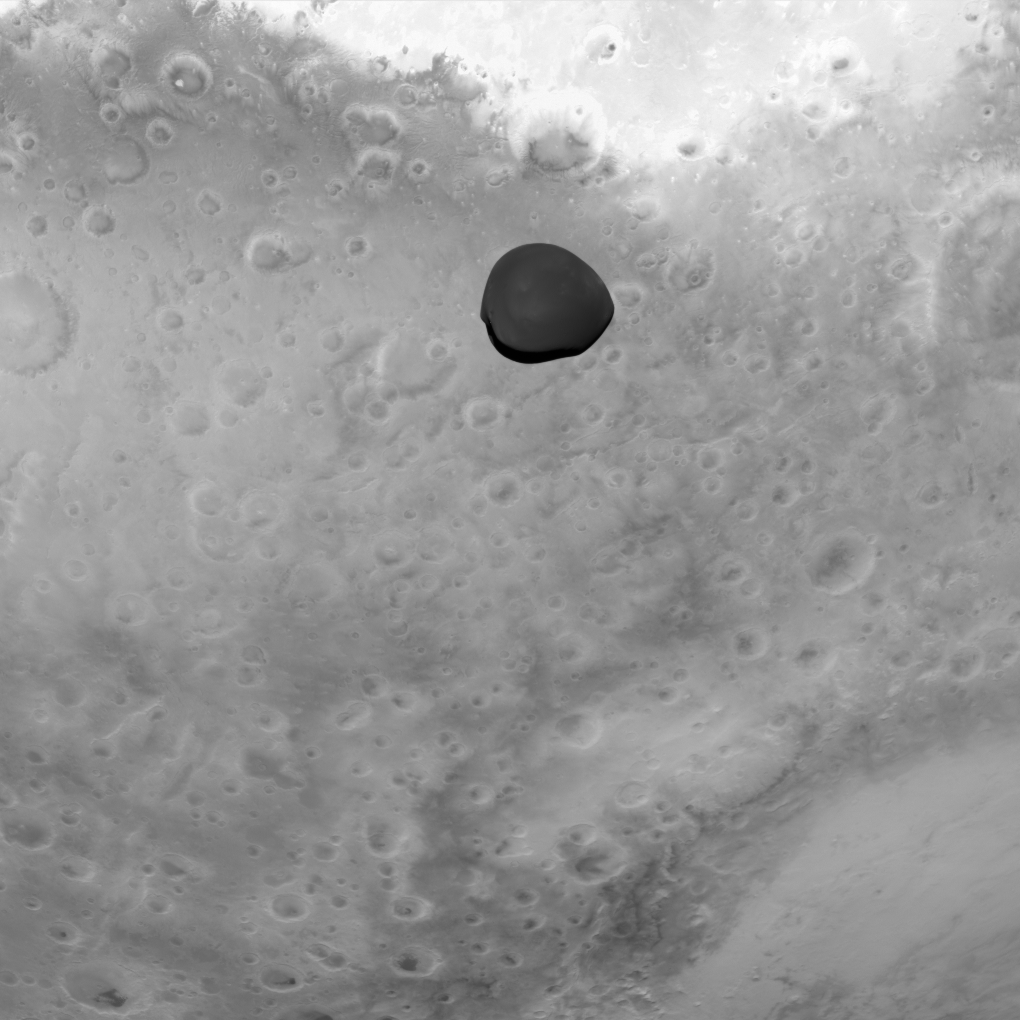 Imagen en blanco y negro de la luna marciana Deimos flotando sobre la superficie de Marte, capturada por la misión Hera. La pequeña luna aparece oscura y definida contra el fondo brillante y craterizado del planeta.